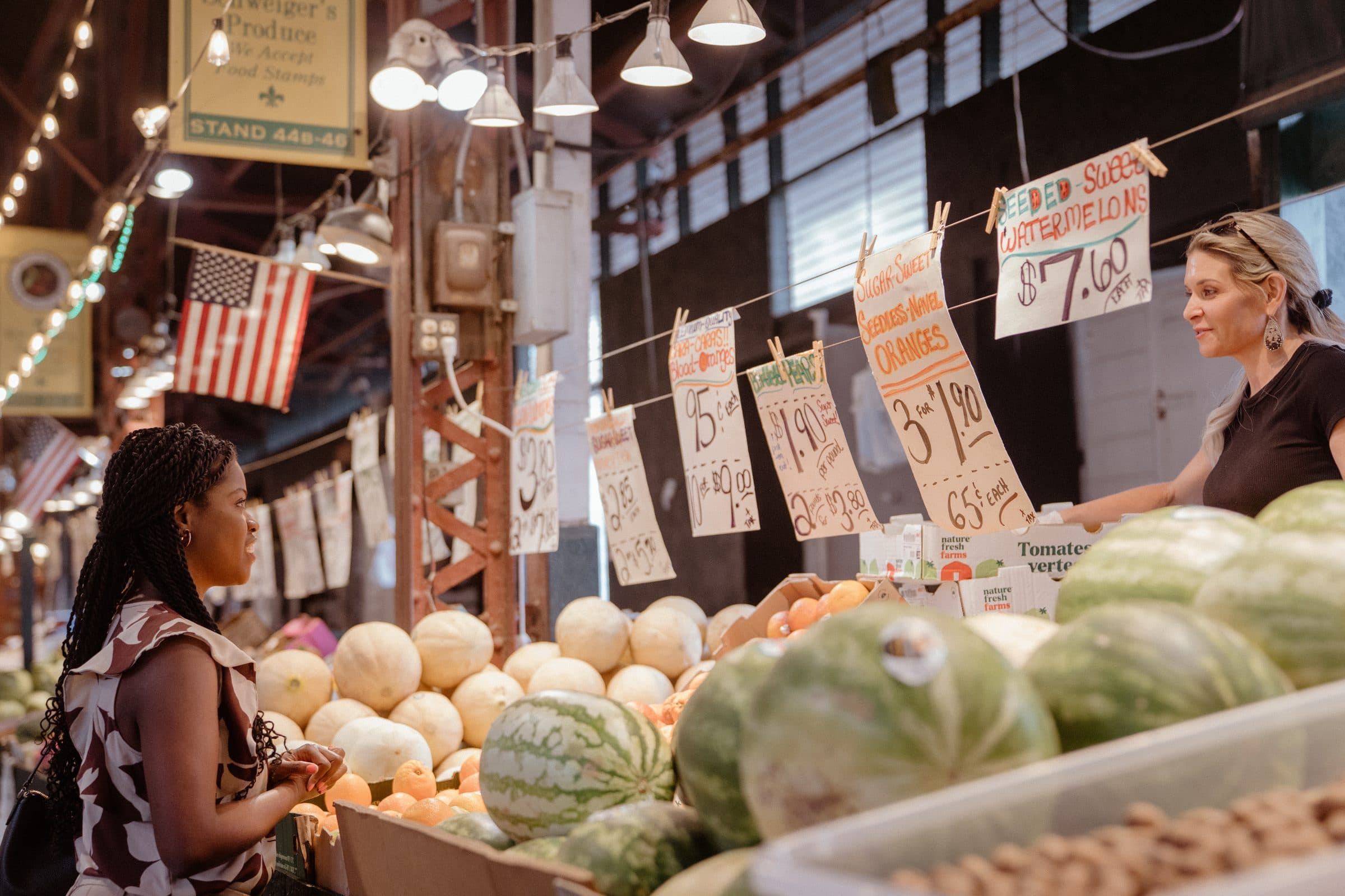 Jami Cox Antwi at a produce stall at the market, talking with the vendor